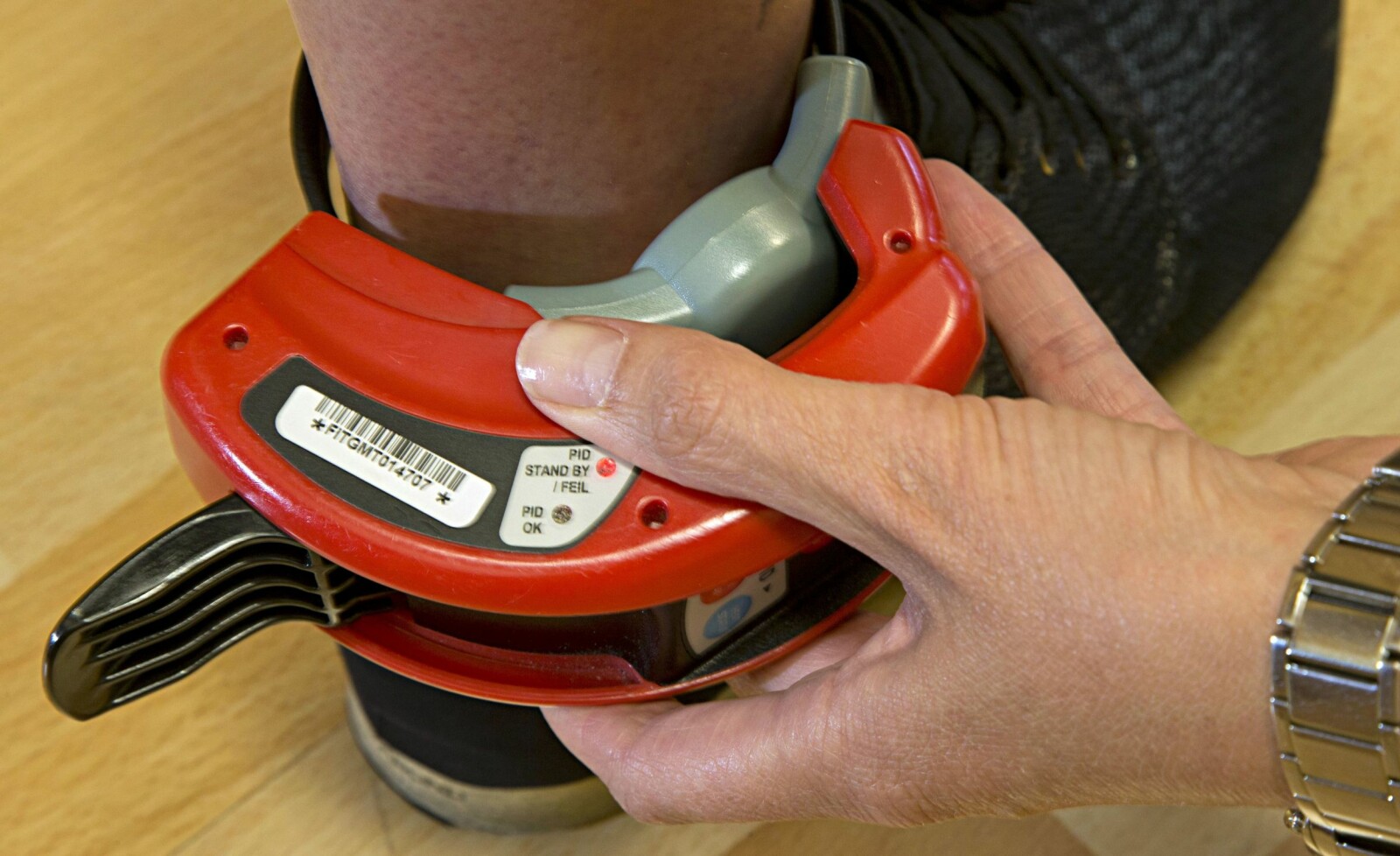 <b>EN FOTLENKE TIL:</b> Slik ser det ut når fotlenken monteres på ankelen. Den røde redskapen låser den til foten. <b>EN FOTLENKE TIL:</b> Slik ser det ut når fotlenken monteres på ankelen. Den røde redskapen låser den til foten.